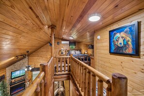 Ein Holzinnenraum mit Treppe, Kamin und Fernseher.