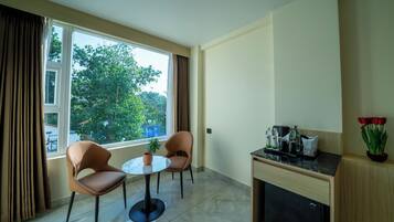 A small, modern room with two chairs, a round table, a potted plant, a coffee machine, and a cabinet.
