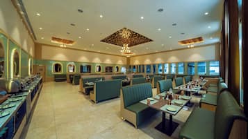 A spacious restaurant with multiple seating areas, including booths and tables, and a buffet line on the left.