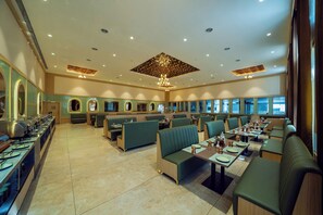 A spacious restaurant with multiple seating areas, including booths and tables, and a buffet line on the left.