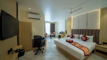 A hotel room with a bed, desk, chair, and a TV.