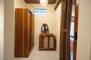 A hallway with a wooden wardrobe, a vanity with a mirror, and a window with decorative glass. - Randama Villa with Private Pool and Kitchenette (Tegallalang)