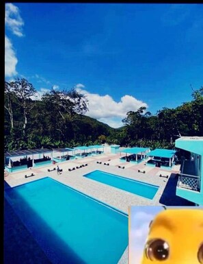 A pool area with multiple sections and covered seating areas, surrounded by greenery. - Paraíso Vacacional FERNANDO (Polo)