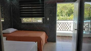 Un dormitorio con cama, ventana y balcón.