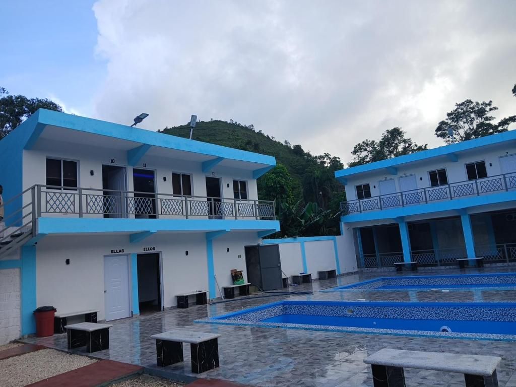 A building with a blue and white color scheme, multiple balconies, and a courtyard with a pool.