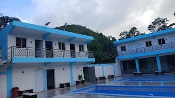 A building with a blue and white color scheme, multiple balconies, and a courtyard with a pool.