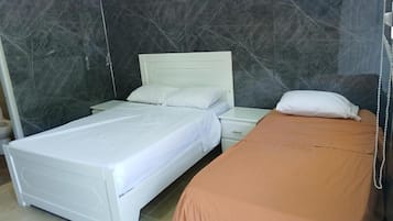 A bedroom with two beds, a white headboard, and a marble wall.