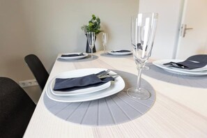 A dining table set with plates, cutlery, and a glass. - Wohnung in Zell (Zell am Main)