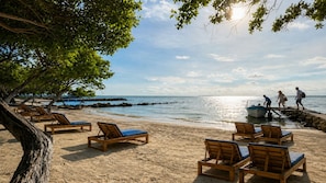 Una playa con sillones de madera y costa rocosa.