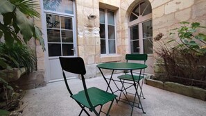 Un cortile con un tavolo, due sedie, un muro in pietra e una porta.