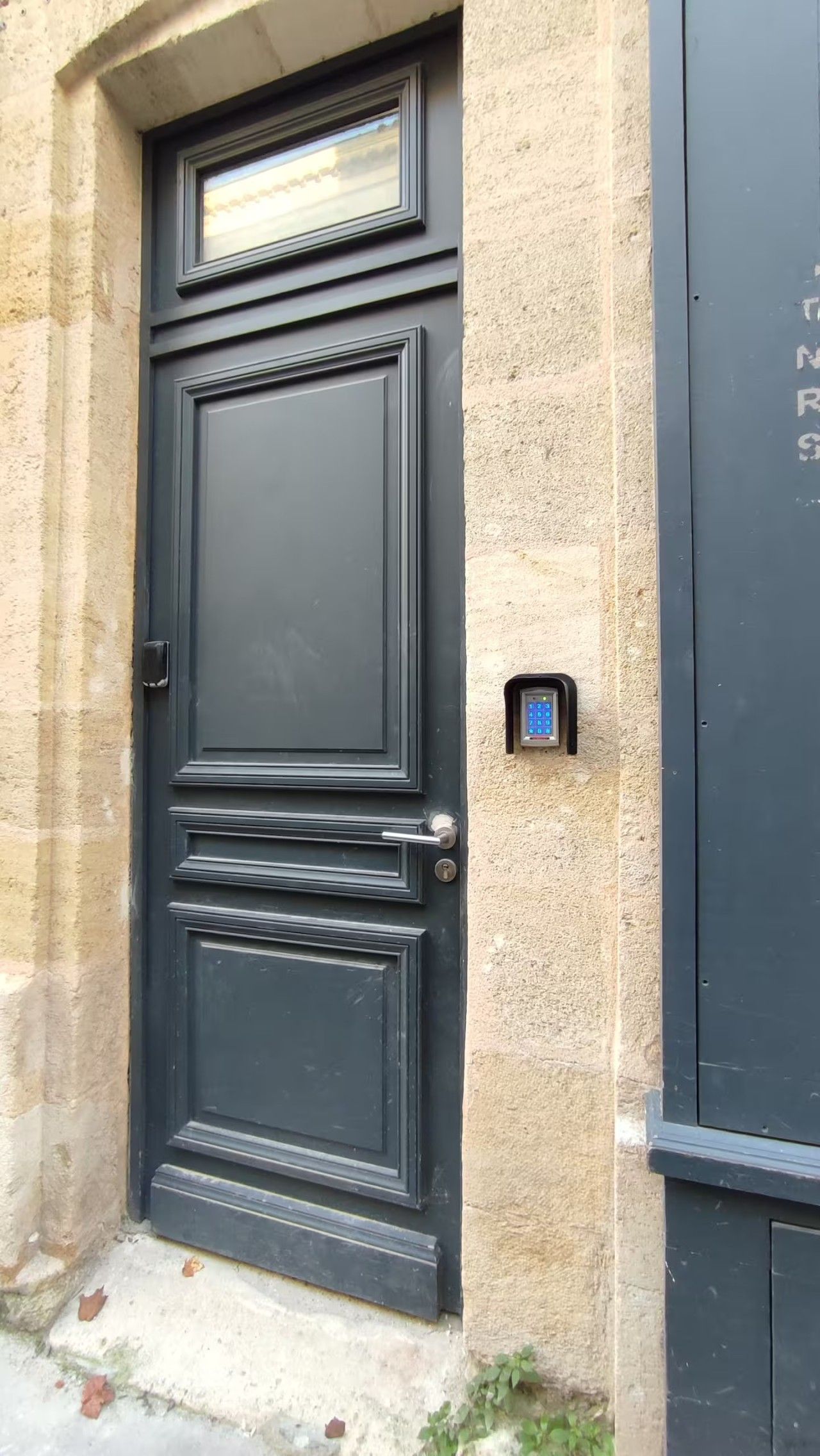 Una porta nera con una serratura a digitare e un piccolo oblò sopra.