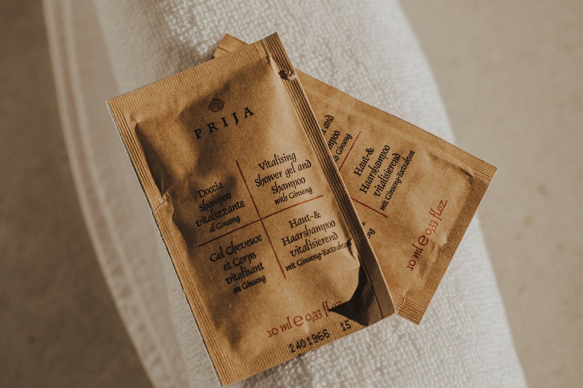 A white towel with two brown packets labeled "PRIJA" containing various hair care products.