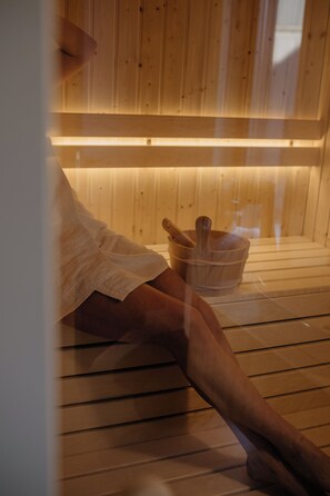 A sauna room with wooden benches and a wooden bucket with a mallet. - FlowFort (Wojcieszyce)