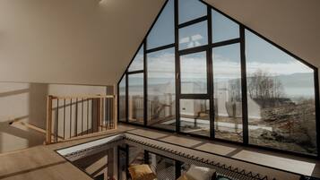 A spacious room with a large window offering a view of a mountainous landscape.
