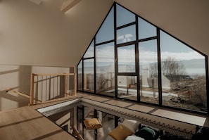 A spacious room with a large window offering a view of a mountainous landscape.