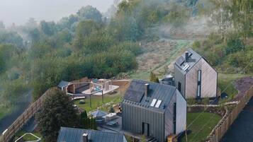Een modern huis met een groot terras, een zwembad en uitzicht op een meer en bergen.