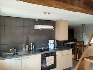 A modern kitchen with a built-in oven, a coffee maker, and a range hood.