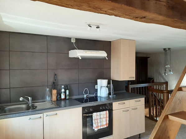 A modern kitchen with a built-in oven, a coffee maker, and a range hood.