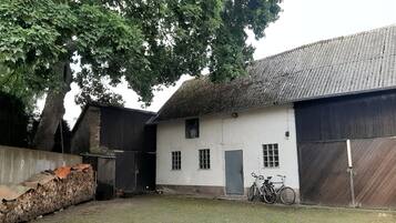 Un bâtiment doté d’un toit de chaume, d’une façade blanche et d’un vélo garé à l’extérieur.