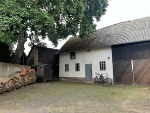 Un bâtiment doté d’un toit de chaume, d’une façade blanche et d’un vélo garé à l’extérieur.