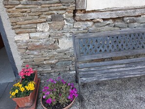 Un mur de pierre avec un banc en bois et deux jardinières ornées de fleurs.