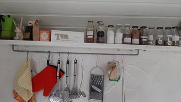 A kitchen shelf with various kitchen utensils and bottles of tea and coffee.