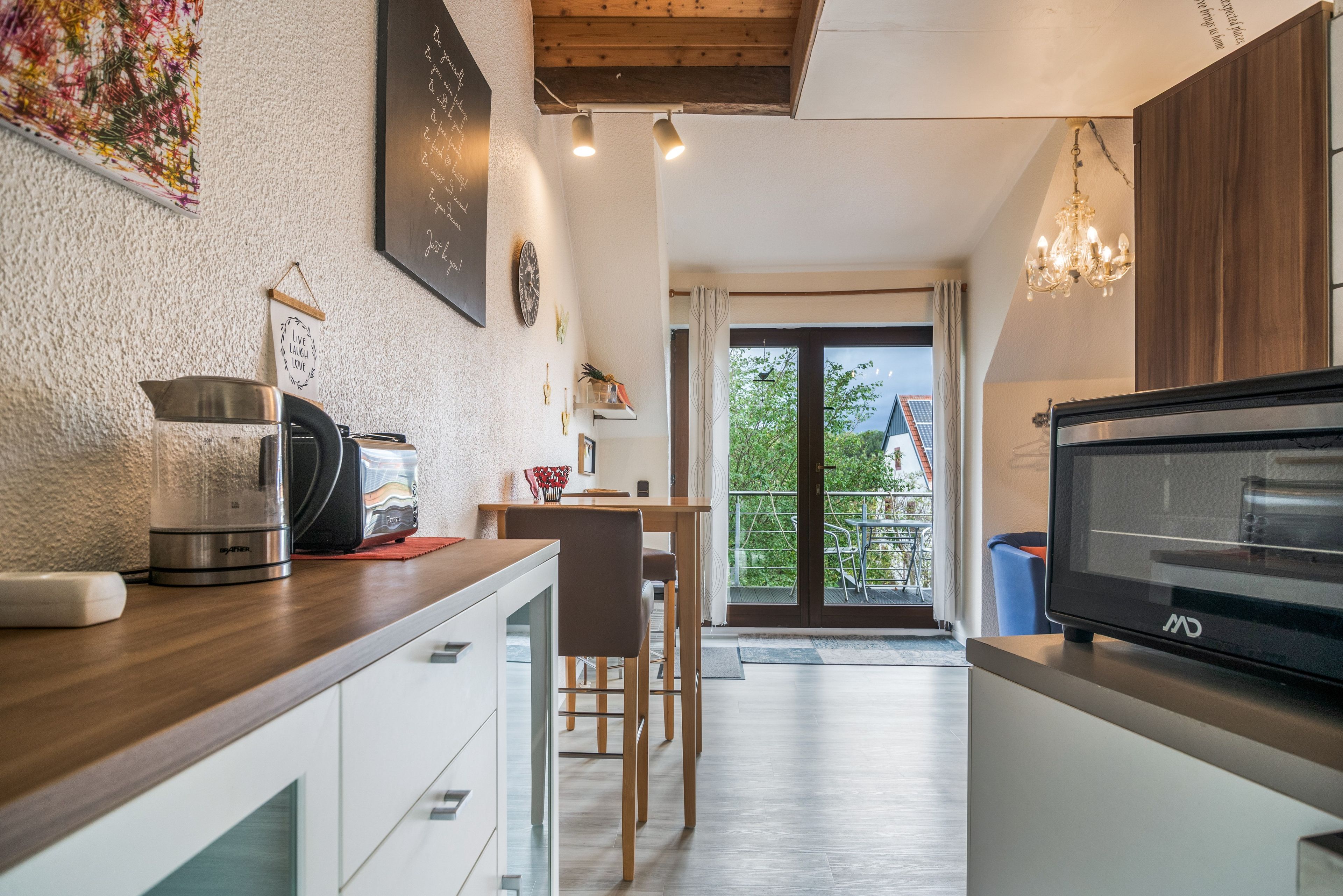 Une cuisine moderne avec un coin repas, une vue sur l’extérieur et un lustre.