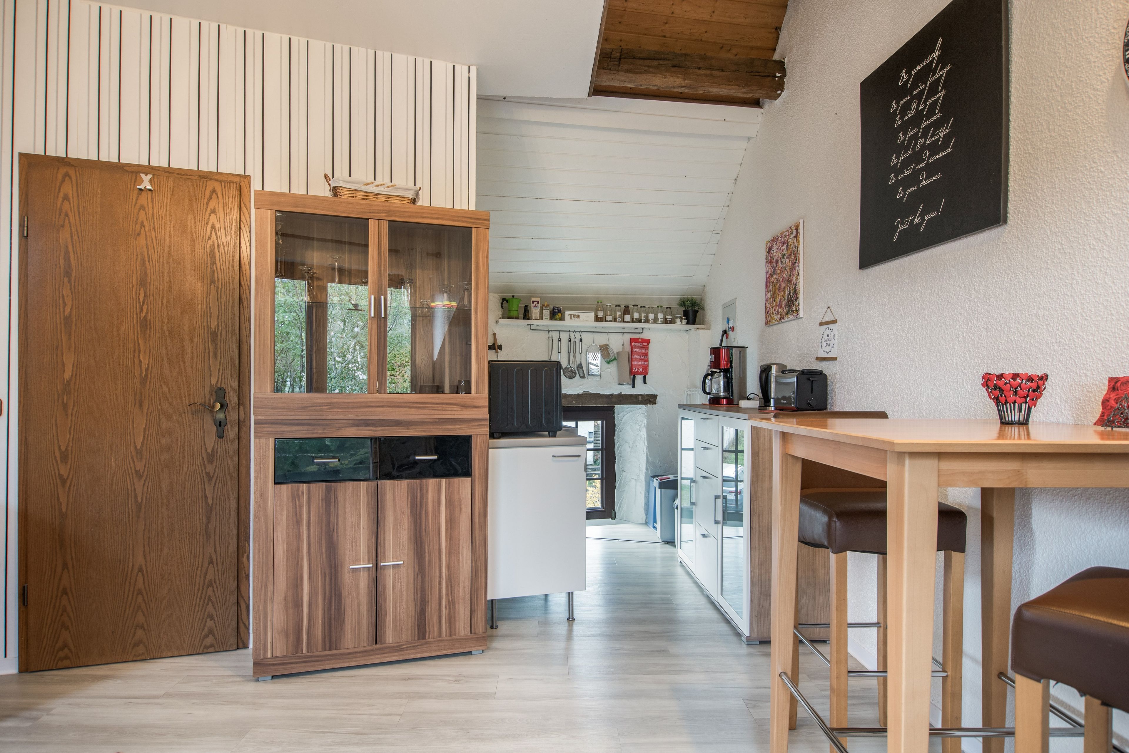 Une cuisine moderne avec des meubles en bois, un coin repas doté d’un banc et une vue sur l’extérieur.