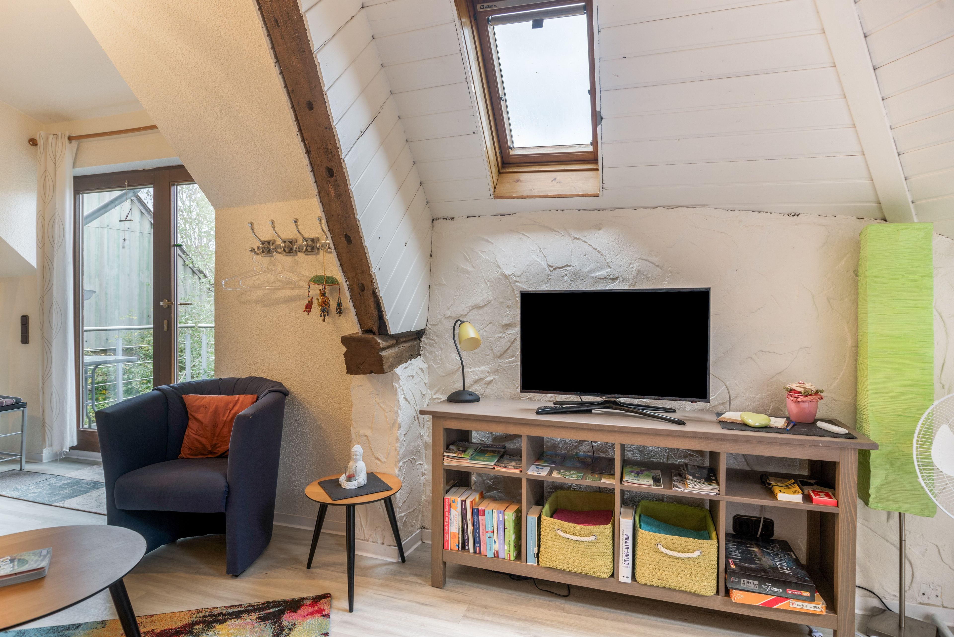 A cozy living room with a television, bookshelves, and a small table.