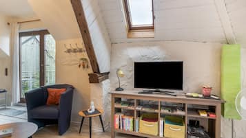 A cozy living room with a television, bookshelves, and a small table.
