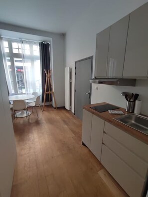 A modern kitchen with a wooden countertop, a built-in oven, and a stainless steel sink. - Apartment in the heart of the Chartrons (Bordeaux)