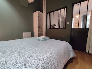 A bedroom with a bed, a wardrobe, a mirror, and a window. - Apartment in the heart of the Chartrons (Bordeaux)