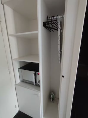 A white closet with open shelves, a hanging rack, and a built-in appliance. - Charmant studio aux Chartrons avec climatisation (Bordeaux)