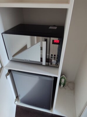 A microwave oven with a digital display and control panel, placed on a shelf above a cabinet. - Charmant studio aux Chartrons avec climatisation (Bordeaux)