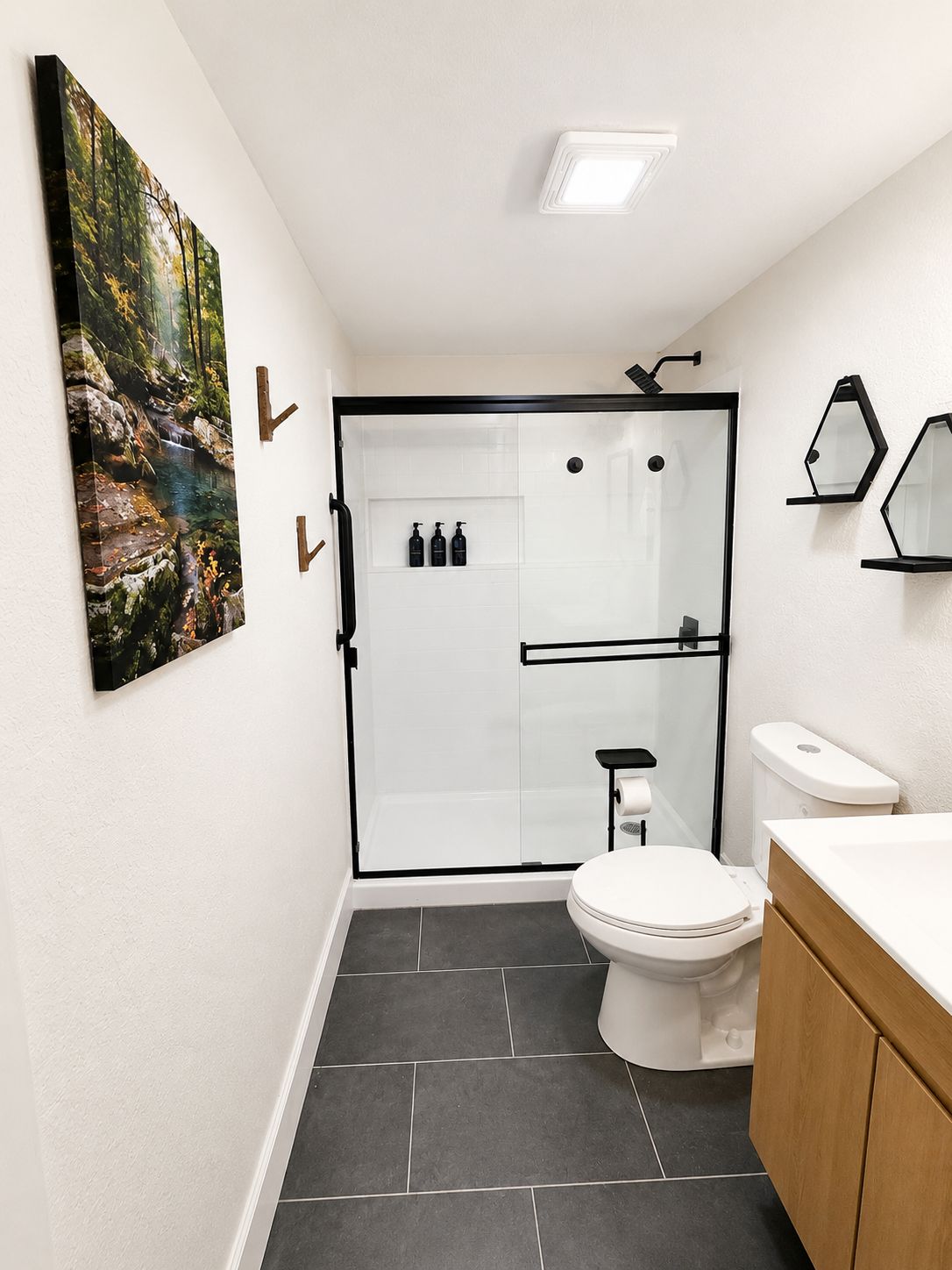 A modern bathroom with a glass shower enclosure, a toilet, and a sink.