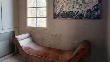 Una stanza con una grande finestra, una panca in pelle marrone e un quadro astratto dai colori vivaci appeso alla parete.
