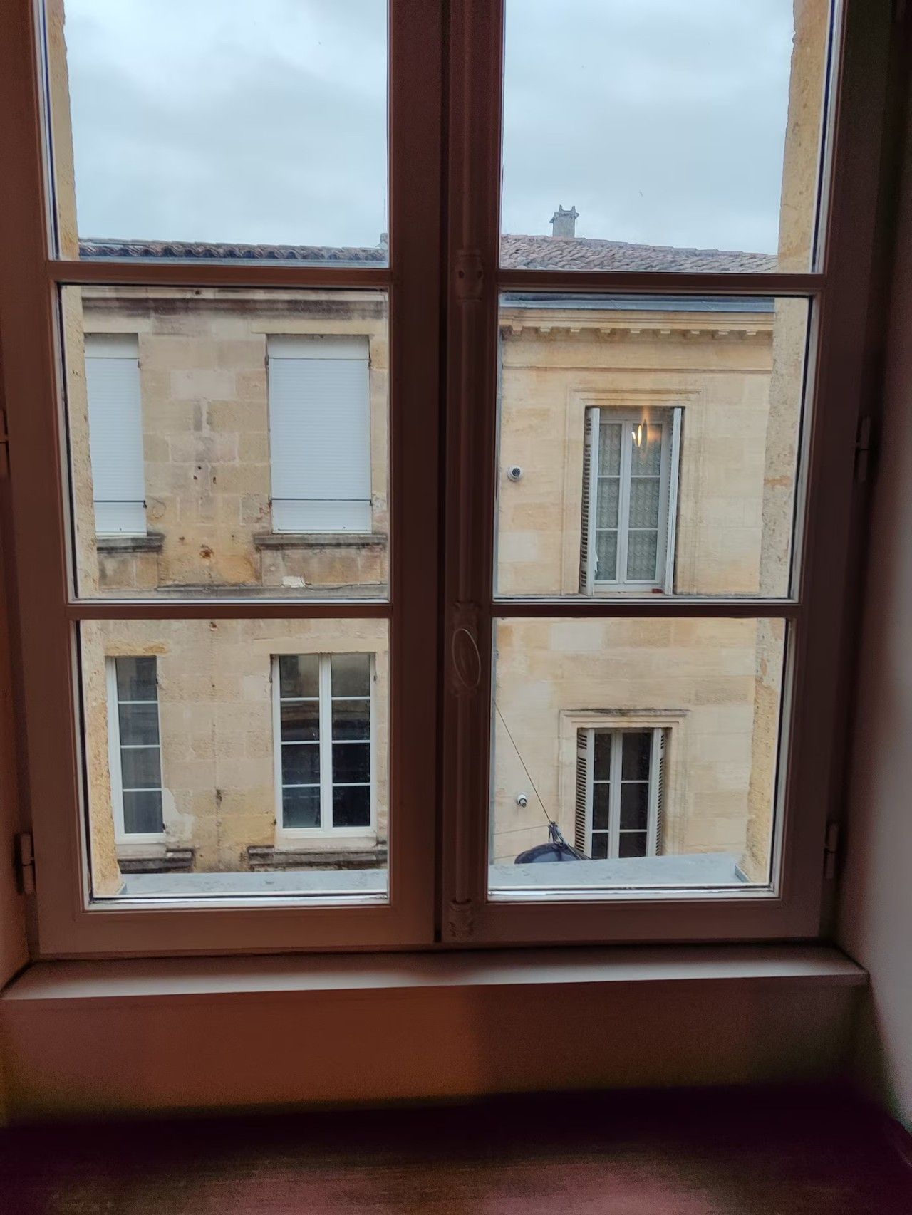 Una finestra che si affaccia su un edificio con molte finestre e un balcone.