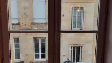 Una finestra che si affaccia su un edificio con molte finestre e un balcone.
