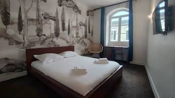 Una camera d'albergo con un letto grande, una scrivania e una finestra con tende.
