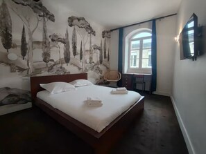 Una camera d'albergo con un letto grande, una scrivania e una finestra con tende.