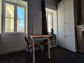 Ein Zimmer mit Tisch, Stühlen, einem Fenster, einem Kleiderschrank und einem Kamin.