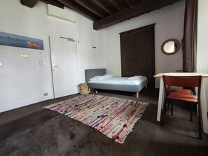 Ein Schlafzimmer mit einem Bett, einem Sessel, einem kleinen Tisch, einem Teppich und einer Tür.