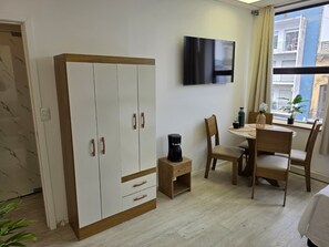 A room with a wardrobe, a coffee maker, a dining table with chairs, and a TV mounted on the wall. - Fully Equipped Apartment in Central Area (Montevideo)