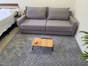 A grey sofa with a wooden coffee table in a room with patterned carpet. - Fully Equipped Apartment in Central Area (Montevideo)
