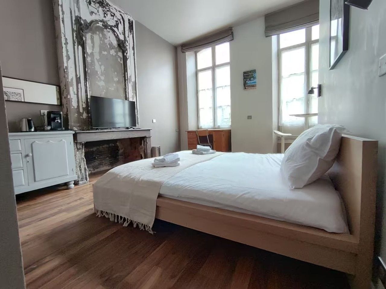 A bedroom with a bed, a desk, and a window.