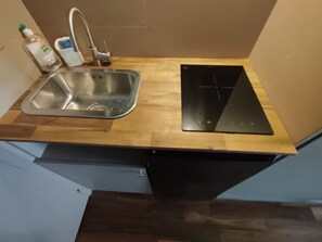 A kitchen with a stainless steel sink, a black induction cooktop, and a wooden countertop. - Studio cosy quartier Chartrons (Bordeaux)