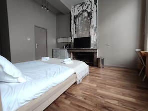A bedroom with a bed, a fireplace, a desk, and a television. - Studio cosy quartier Chartrons (Bordeaux)