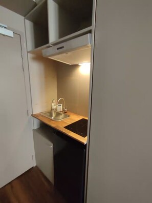 A compact kitchenette with a sink, countertop, and a built-in oven. - Studio cosy quartier Chartrons (Bordeaux)