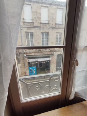 A window with a view of a building facade, including a sign for 'MUSEE DU VIN ET DU NEGOCE'. - Studio cosy quartier Chartrons (Bordeaux)