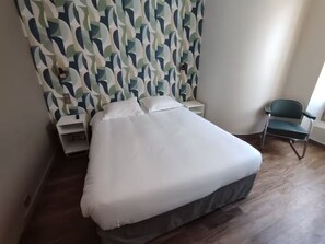 A single bed with a white mattress and pillows, a nightstand, a chair, and a patterned curtain. - Apartment in mythical Chartrons floor 1 (Bordeaux)